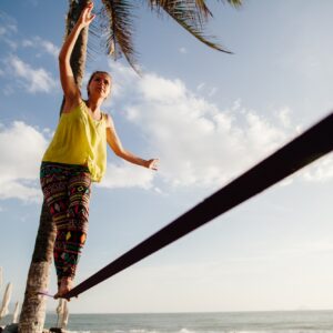 teenage girl balancing on slackline with sky view